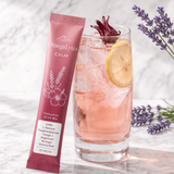 OmegaLytes Calm Hibiscus Rosé sachet beside a tall glass of pink rosé drink with ice, lemon and hibiscus